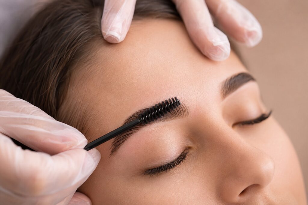 Beautician brushing an eyebrow with a spoolie during brow lamination
